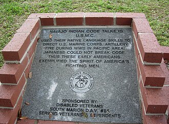 Code talker memorial with etched words: "Navajo Indian Code Talkers USMC. They used their native language skills to direct the US Marine Corps Artillery fire during WWII in the Pacific area. Japanese could not break the code. Thus, these early Americans exemplified the spirit of America's fighting men. Sponsored by: Disabled Veterans South Marion DAV#85 serving veterans and dependents." The memorial also includes the United States Marine Corps emblem.