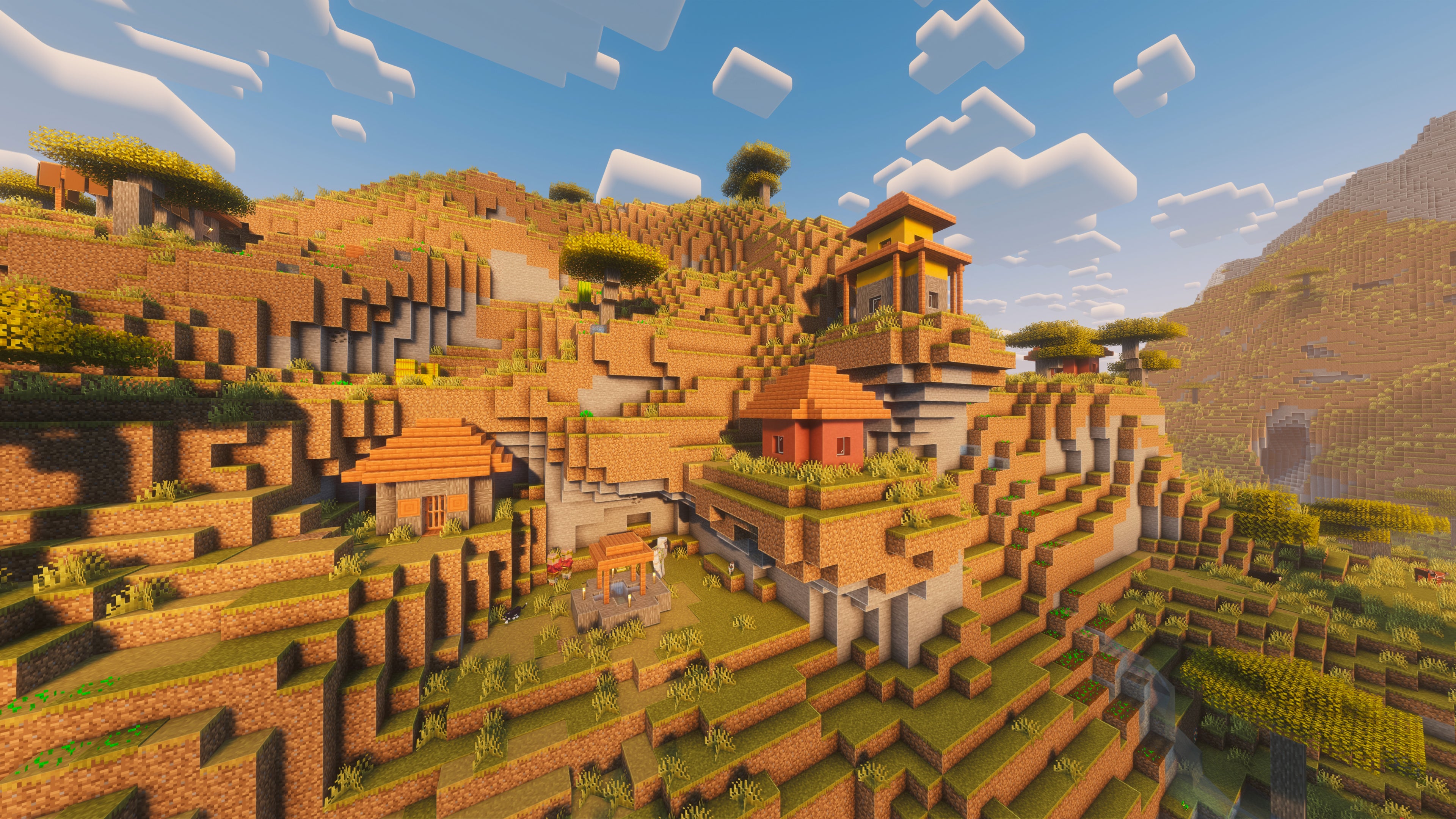 A landscape screenshot of a Minecraft seed, showing a Village built on the side of a Badlands hill.