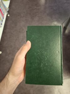 Hand holding a dark green book.
